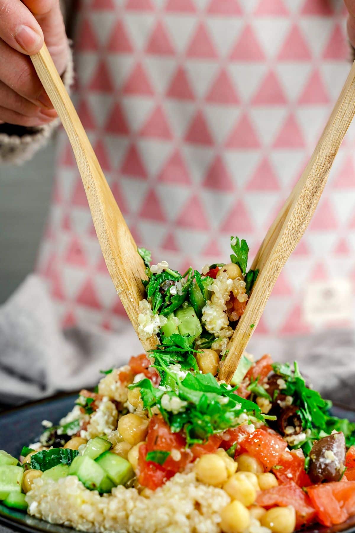 wooden spoons tossing salad ingredients in black bowl