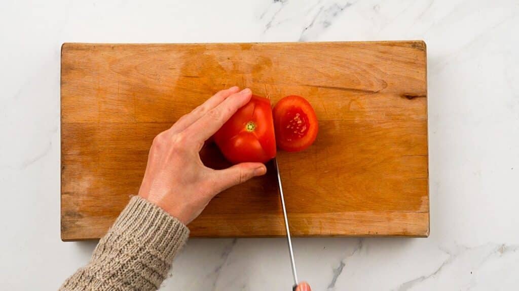 tomato being sliced on cutting board