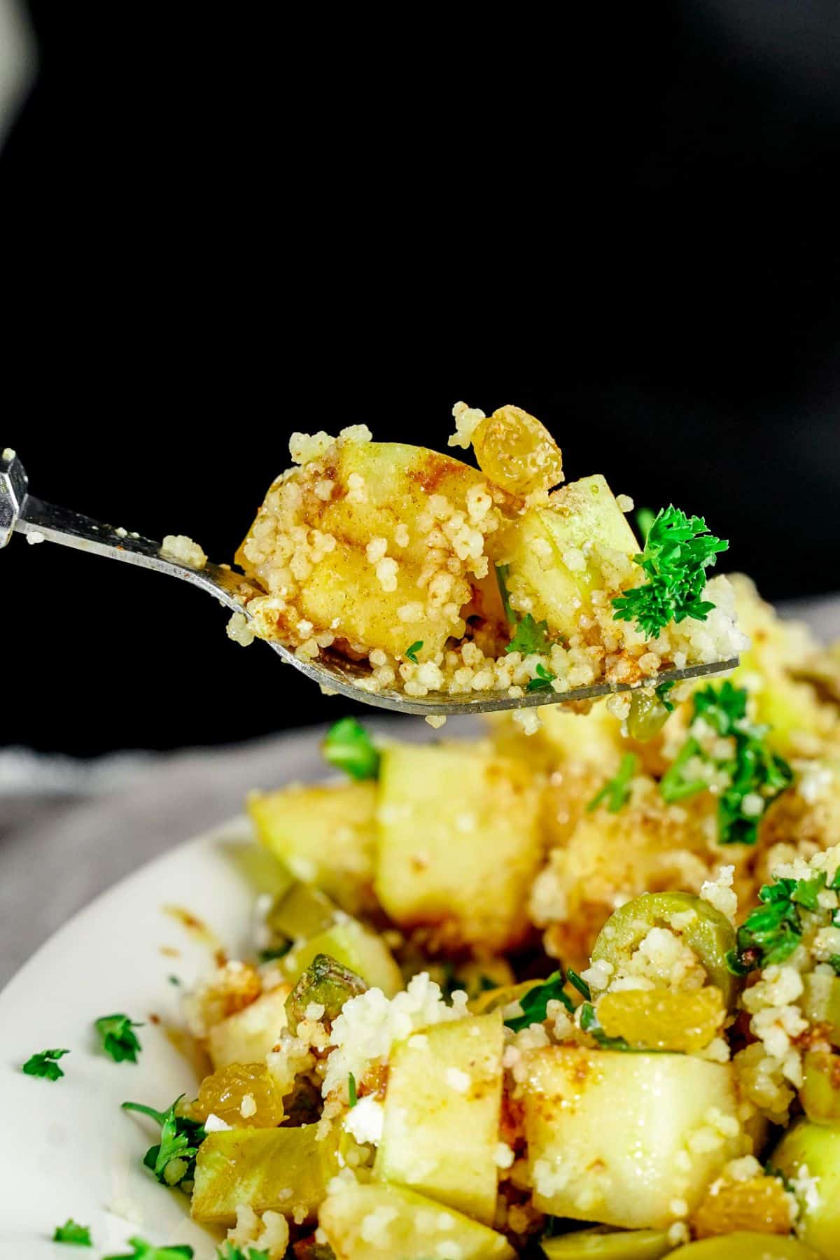 fork of Moroccan couscous salad above white bowl of salad