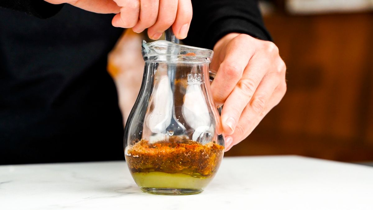 glass jar of salad dressing being whisked