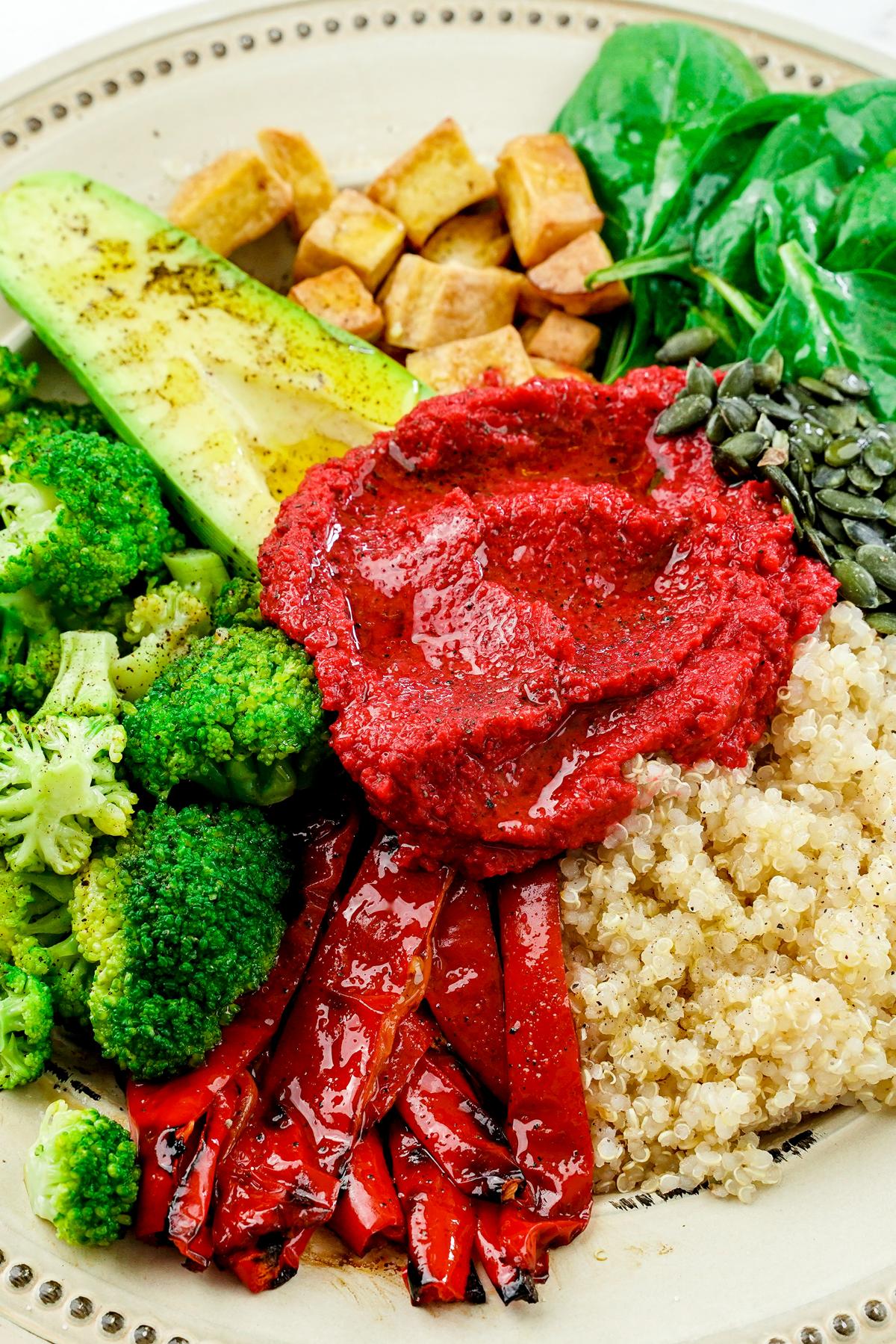 various vegetables on plate with scoop of beet hummus in the middle