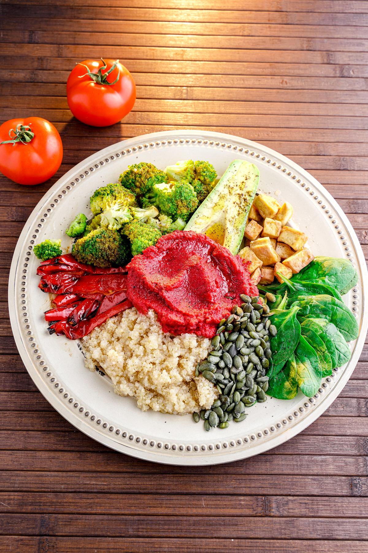 tofu quinoa salad on white plate with dollop of red beet dressing on top