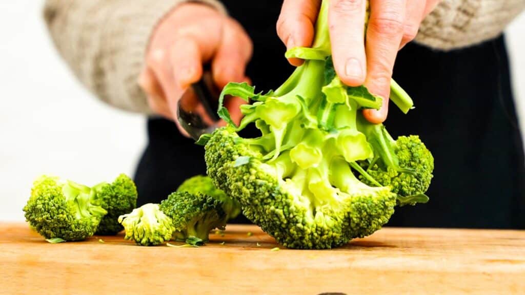 broccoli being cut from stem on cutting board