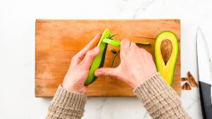 peeling avocado above cutting board
