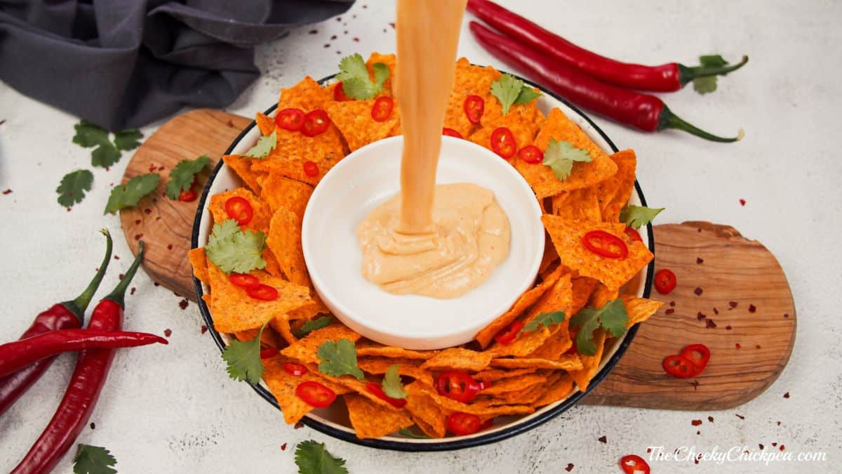 white bowl on platter being filled with cheese sauce