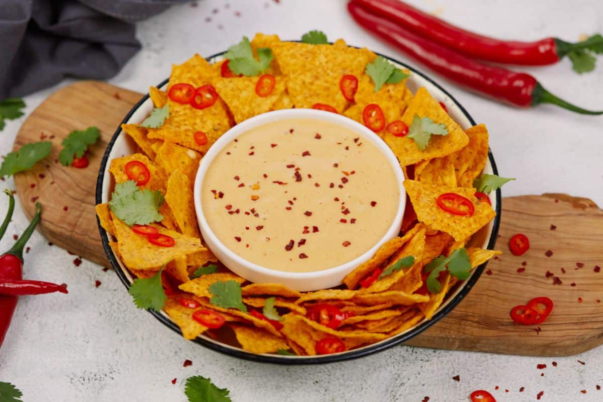 large bowl of chips with vegan cheese sauce in bowl on center of platter