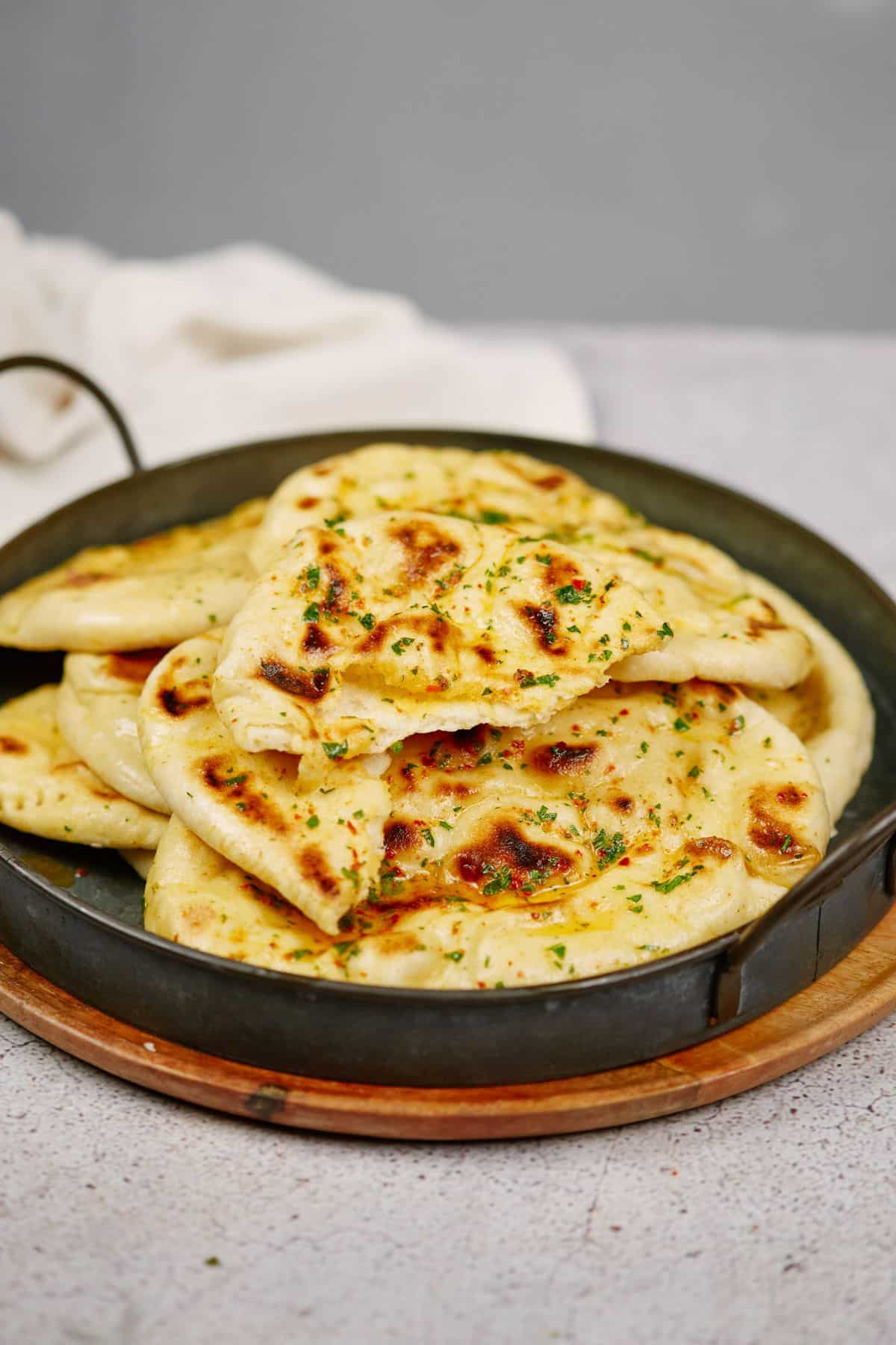naan cooked and laying on black pan on wood cutting board