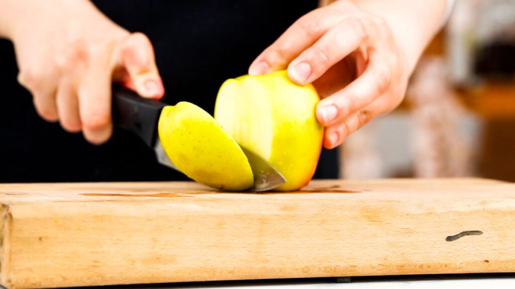 green apple being sliced on cutting board