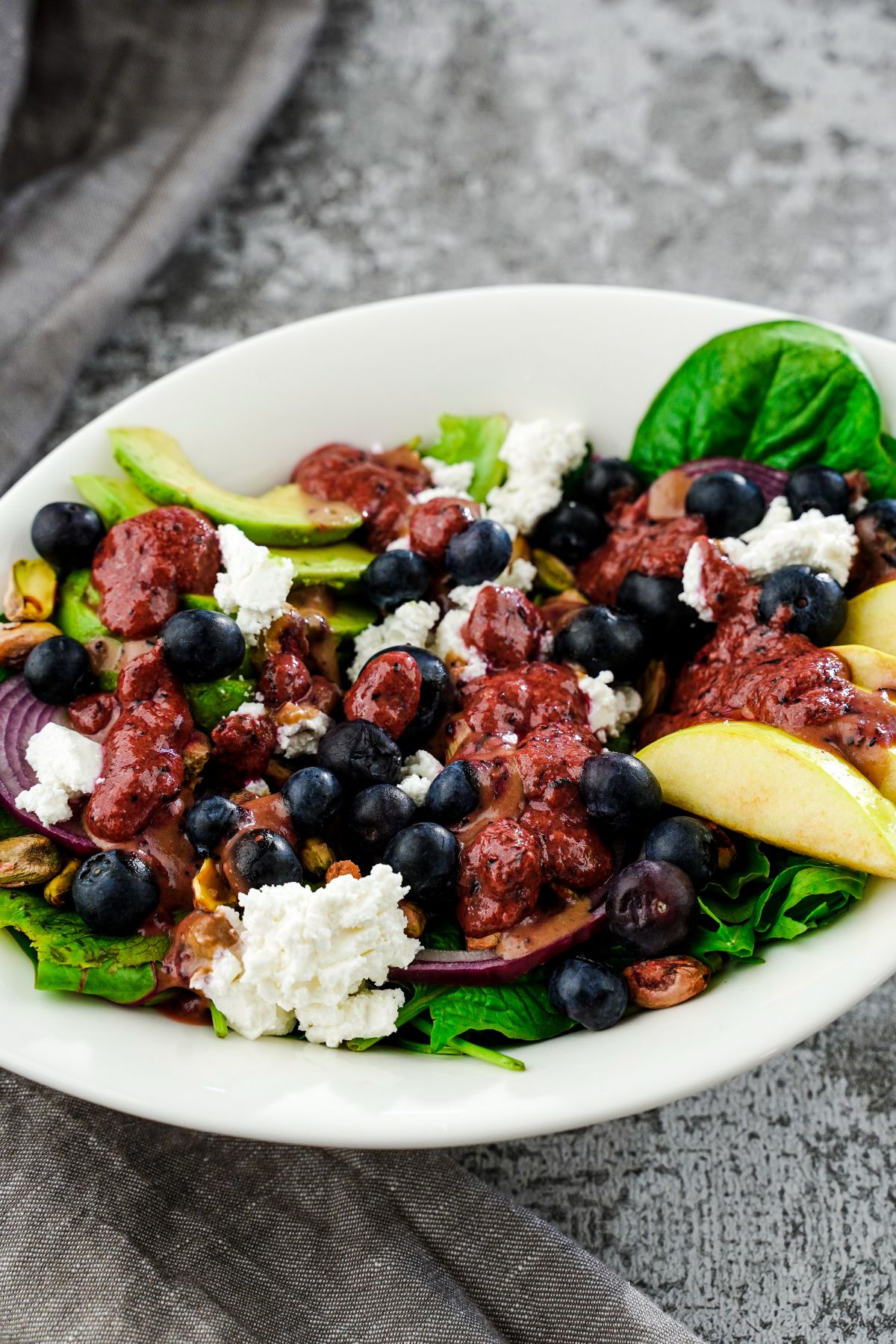 white bowl of blueberry baby salad with vegan feta and apples on top