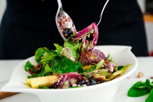 spoon and fork holding up portion of salad with red onion
