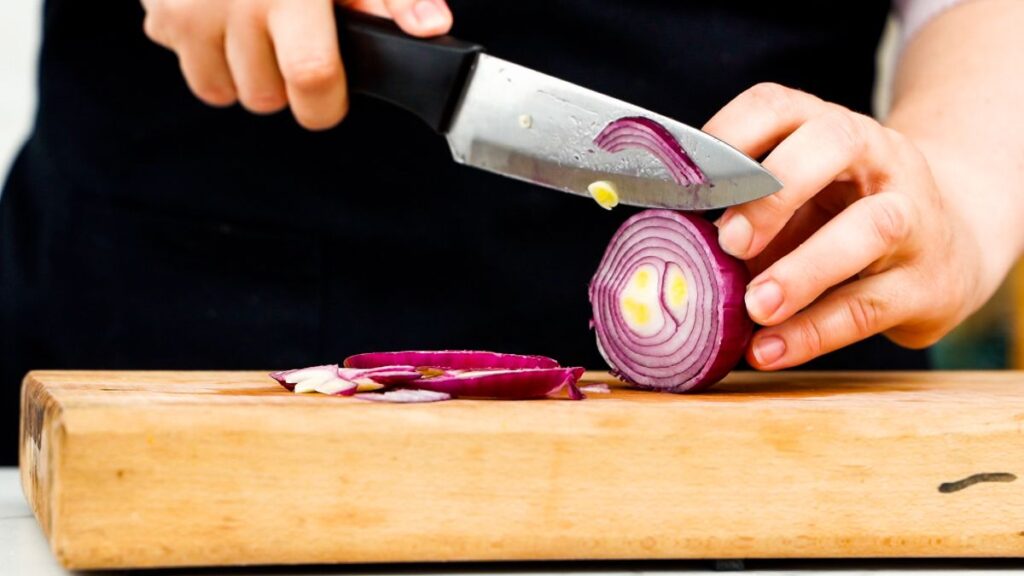 slicing red onion on cutting board