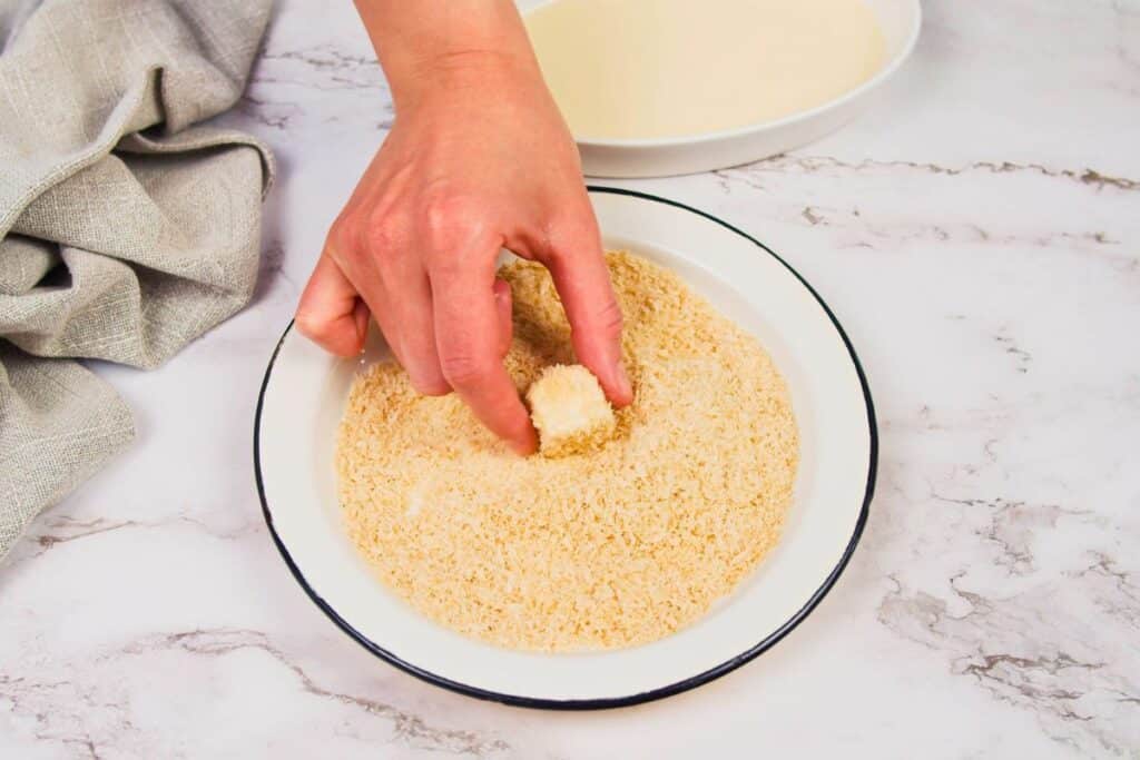 tofu cubed dipping into breadcrumbs