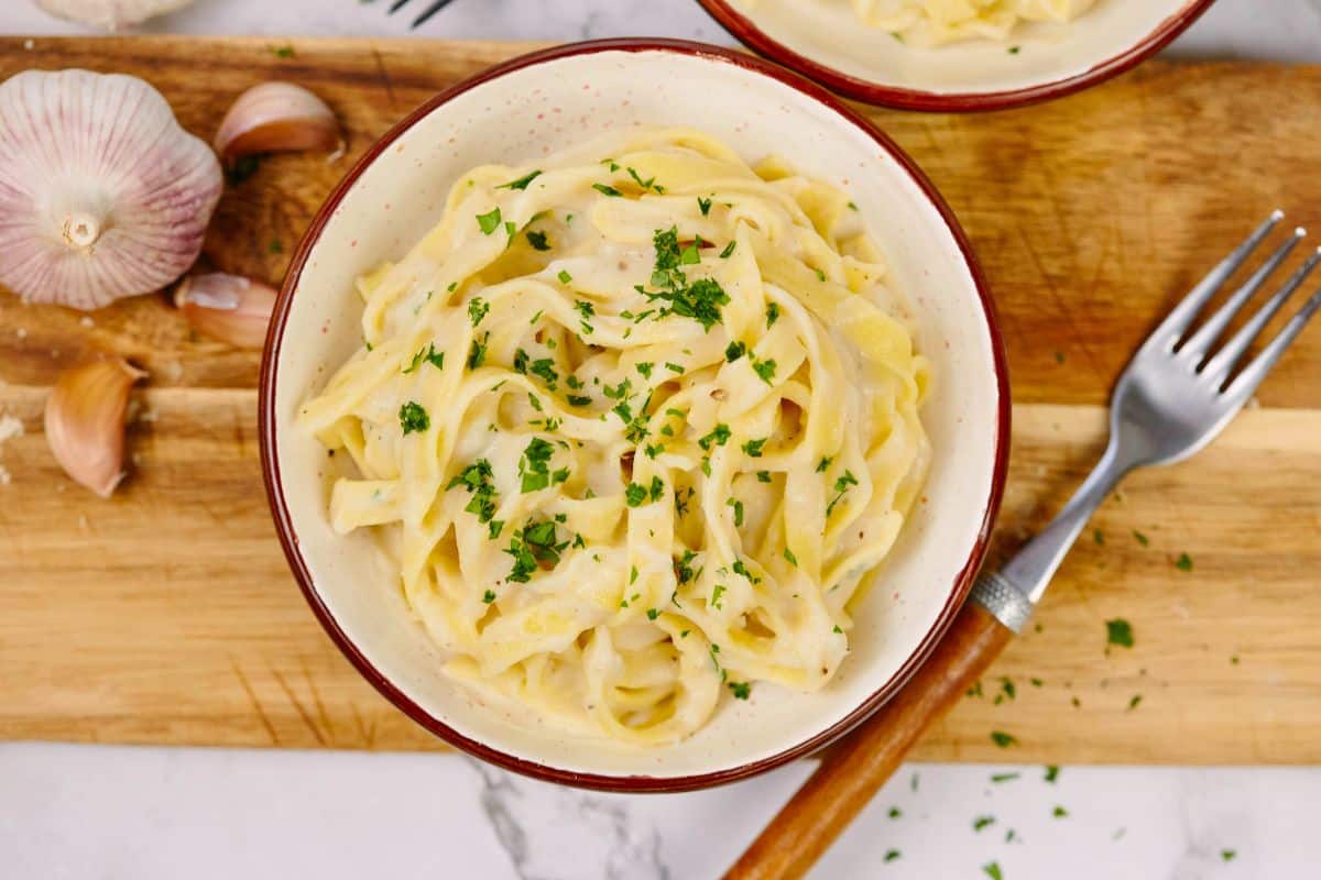 white bowl with red rim filled with cauliflower alfredo and pasta
