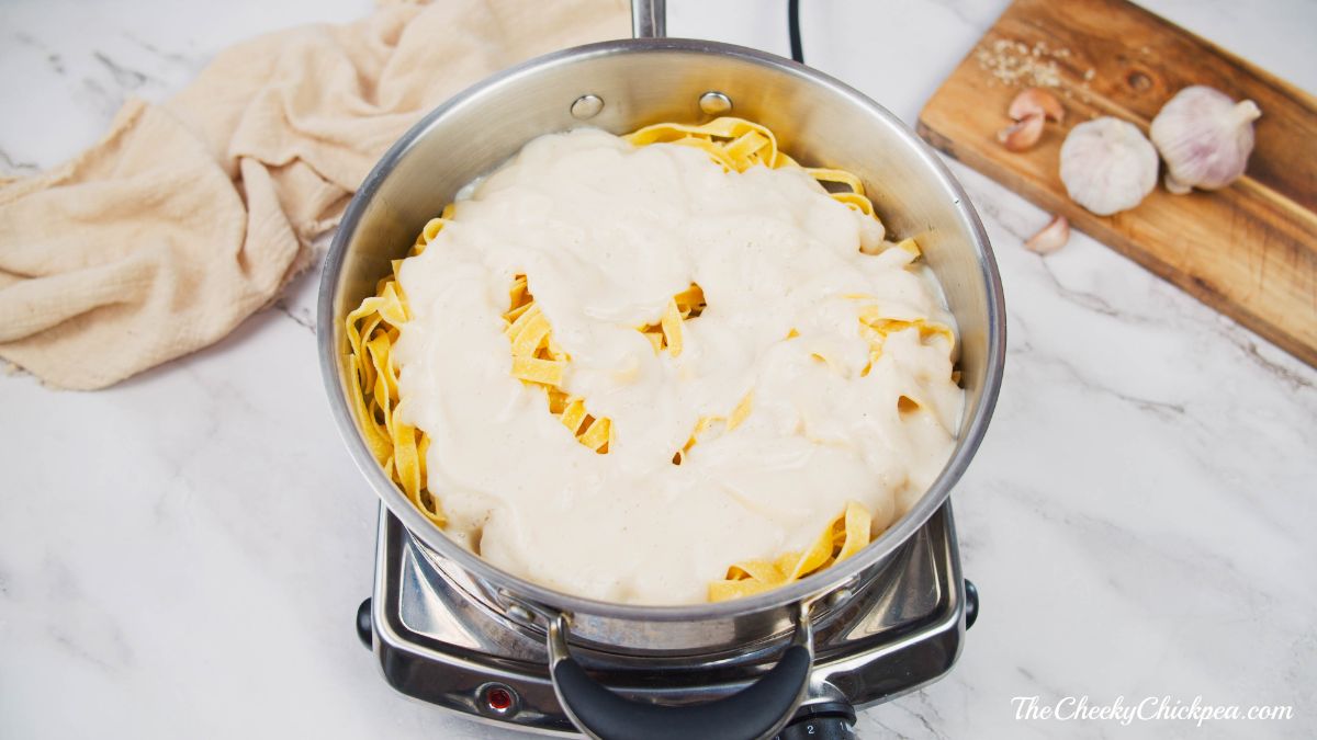 sauce being poured over pasta in pan