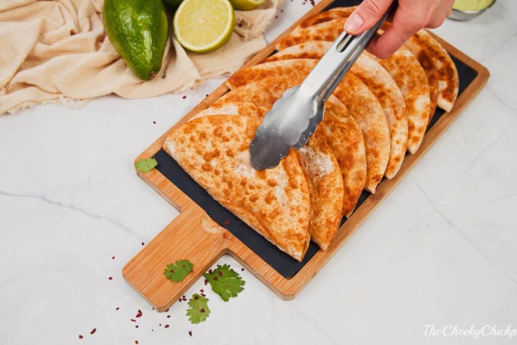 tongs placing tacos on cutting board