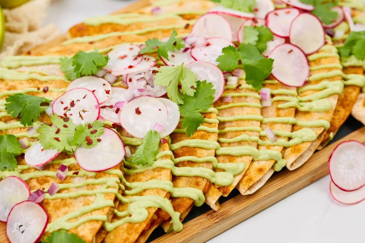 wooden platter of fried ptoato tacos topped by sliced radishes