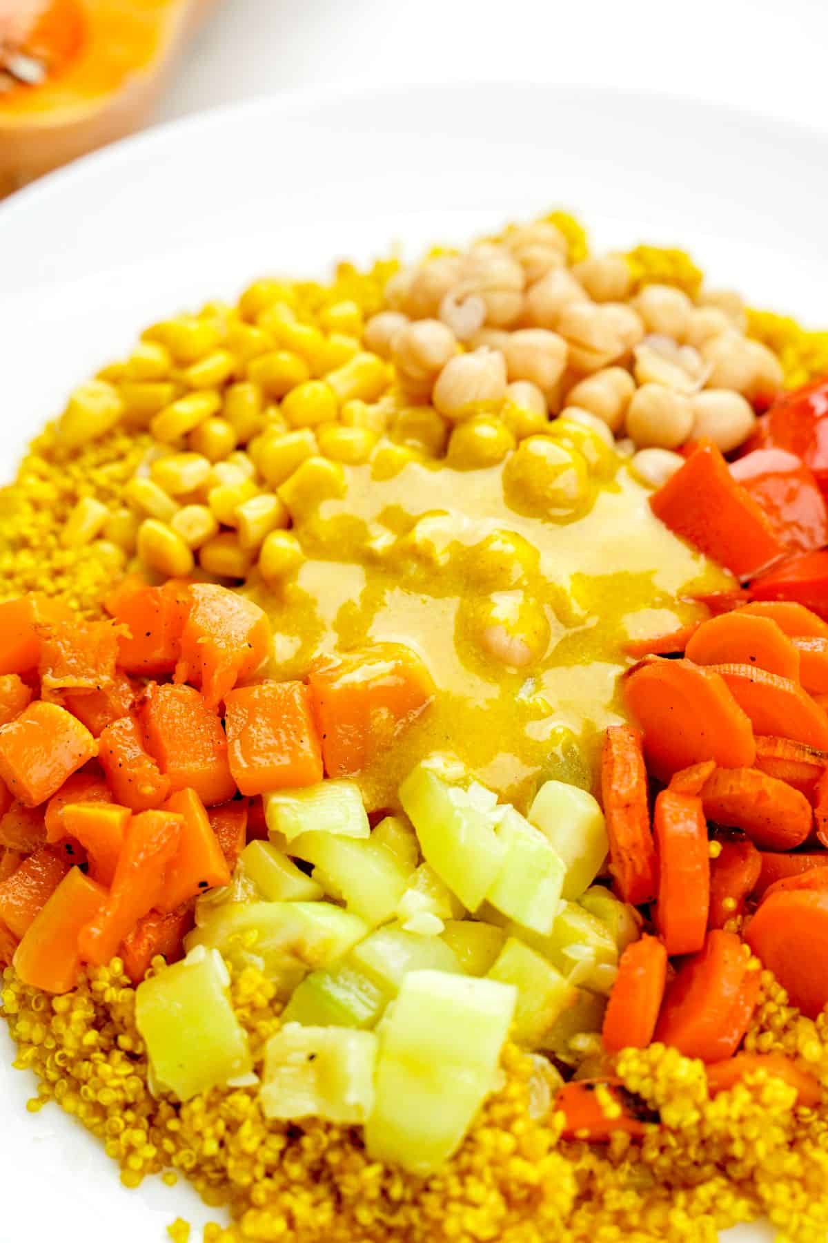 white bowl of salad with quinoa base and vegetables on top