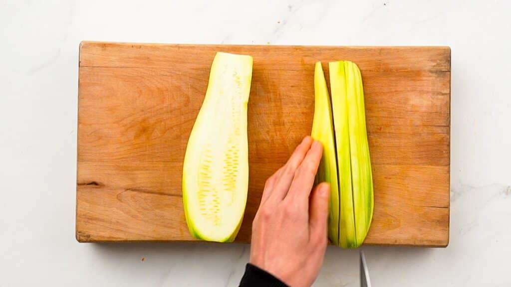 squash being sliced on wooden cutting board