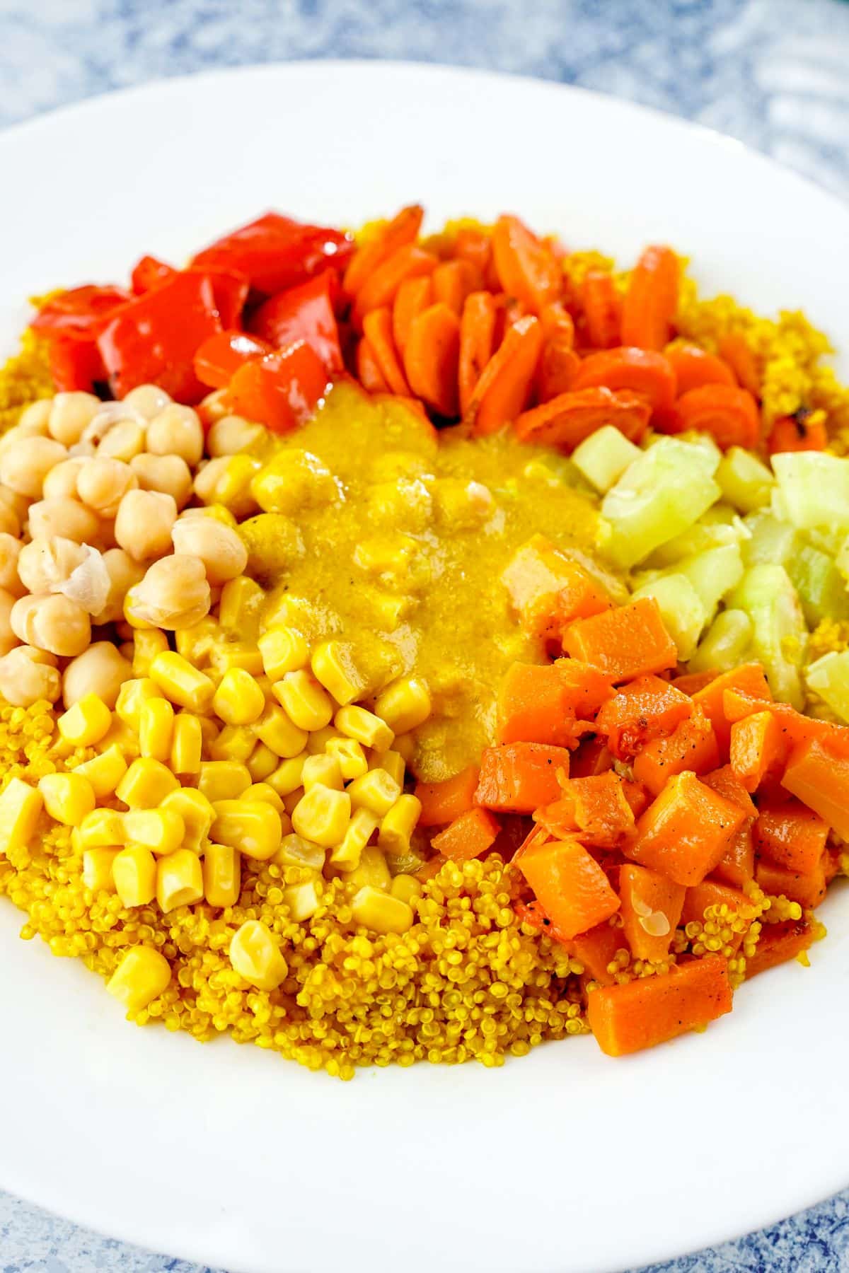 white bowl filled with yellow and orange ingredients including couscous, chickpeas, squash, and more