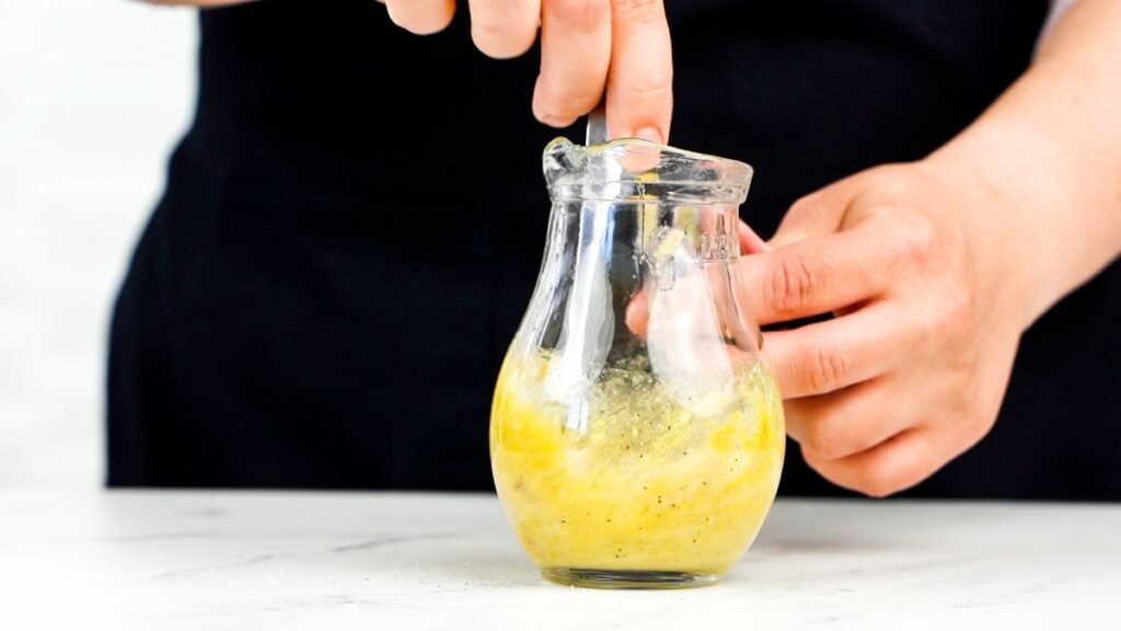 salad dressing being whisked in glass jar