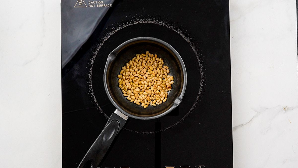 pine nuts in saucepan on black hot plate