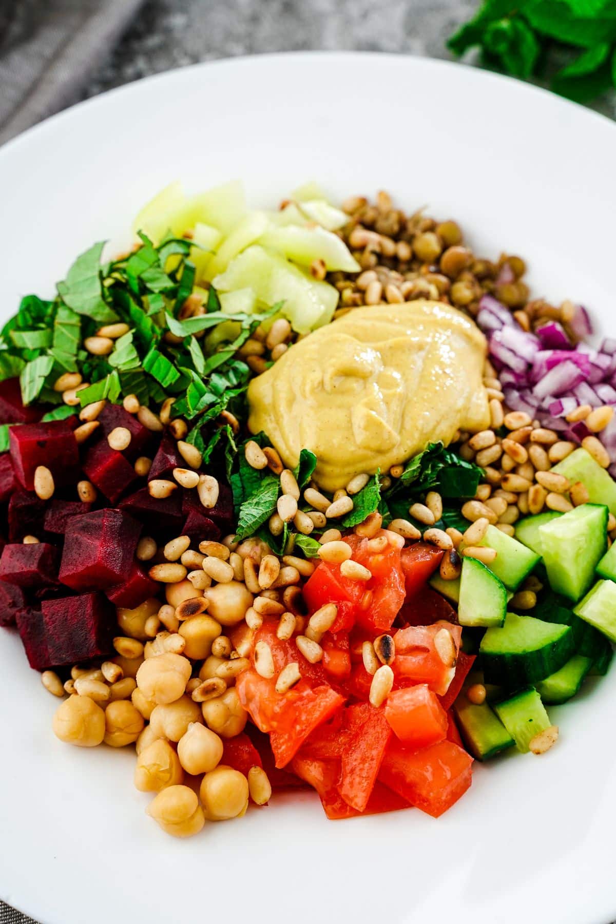 white bowl of lentil chickpea salad topped with tahini dressing