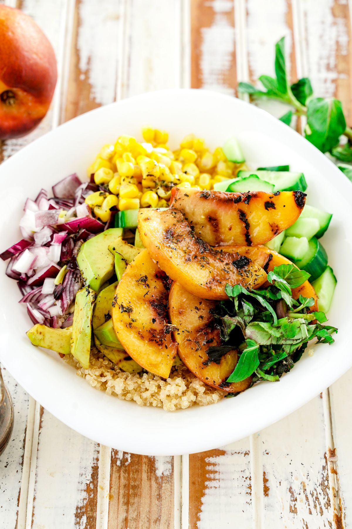 grilled peach quinoa salad in white bowl on wooden table