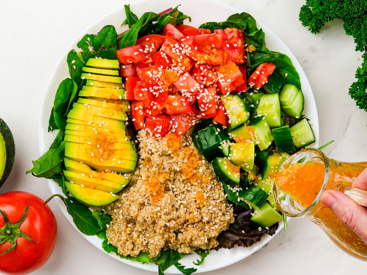 dressing being poured over vegan power bowl