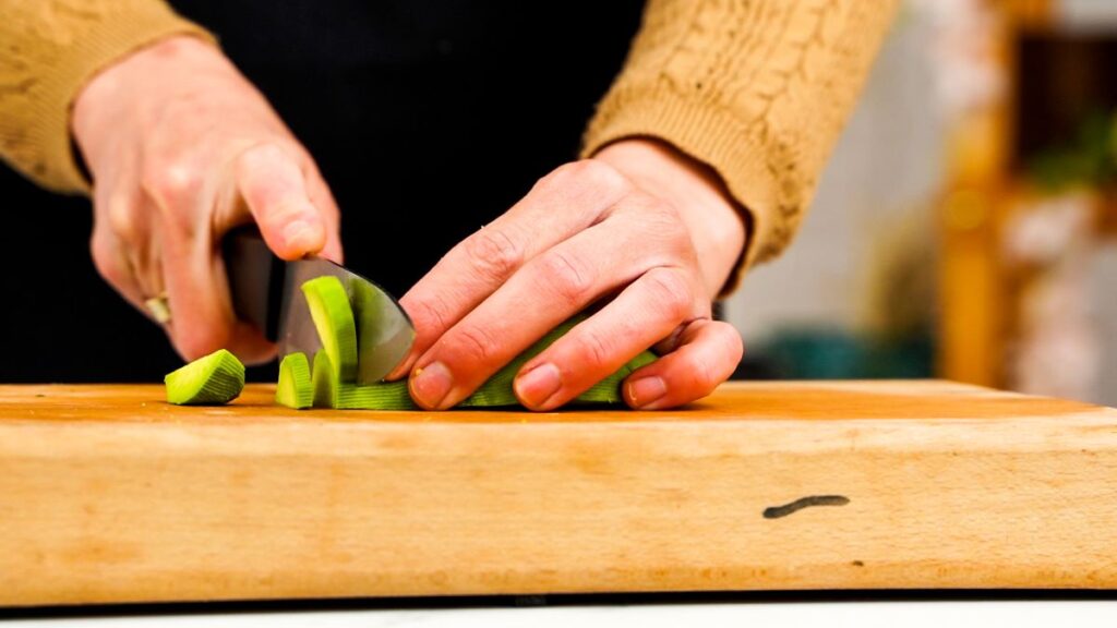 avocado being sliced on wood cutting board