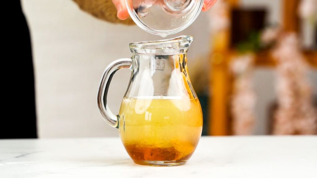 oil being poured into glass jar to make salad dressing