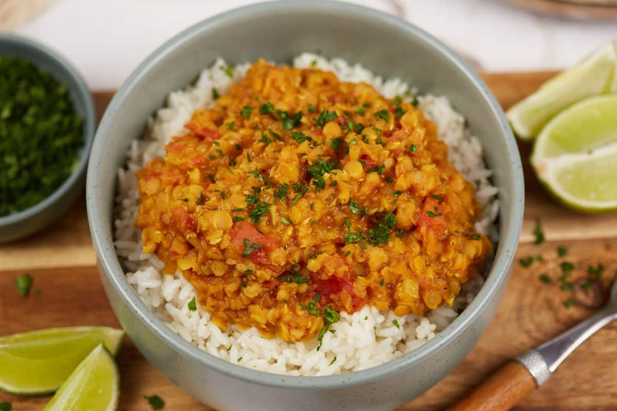 bowl of dahl on top of rice in bowl by lime wedges