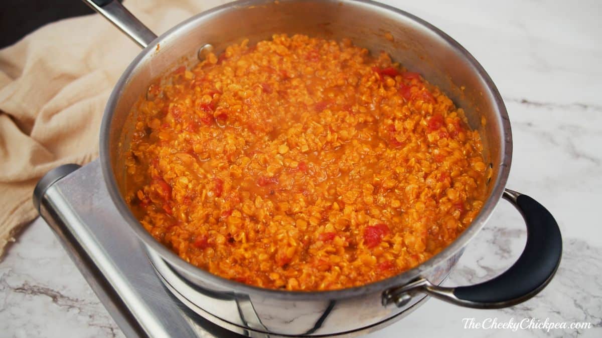 metal stockpot filled with lentil dahl on top of hotplate on table 