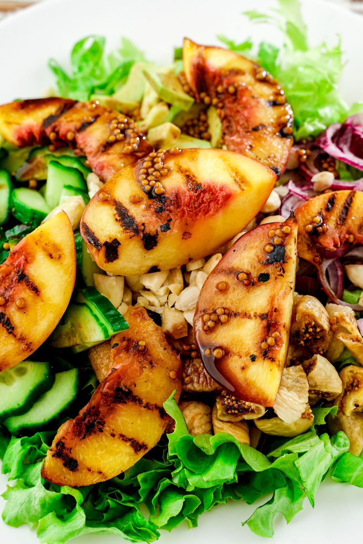 grilled peaches on top of salad on white plate