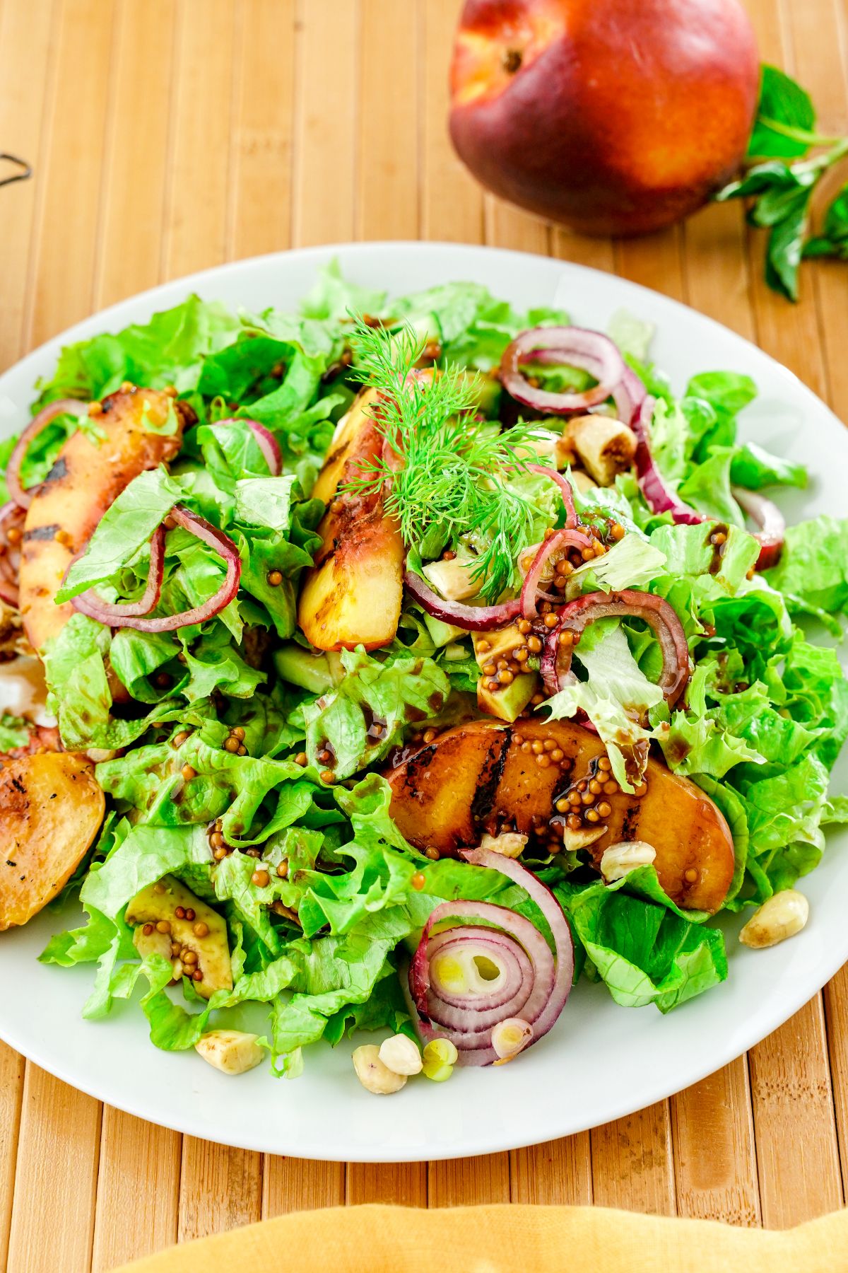 white plate of salad on wooden board with peach in background