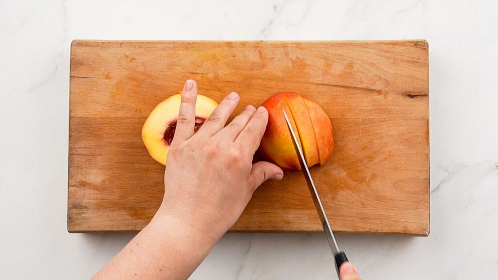 slicing peach in half on wood board