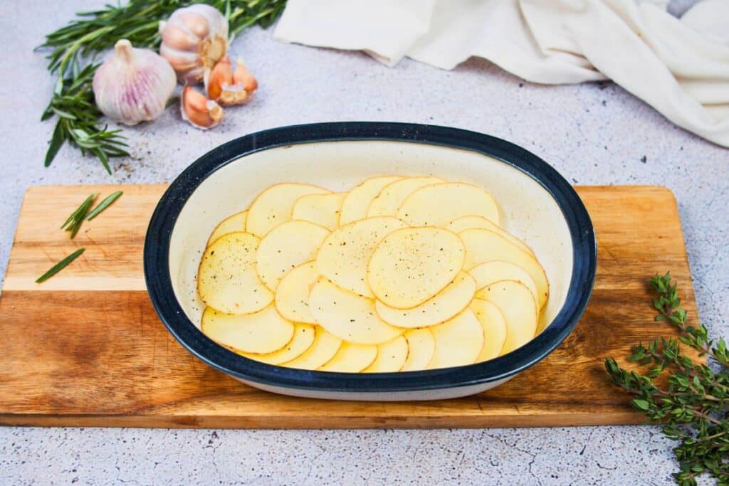 sliced potatoes in bottom of baking dish