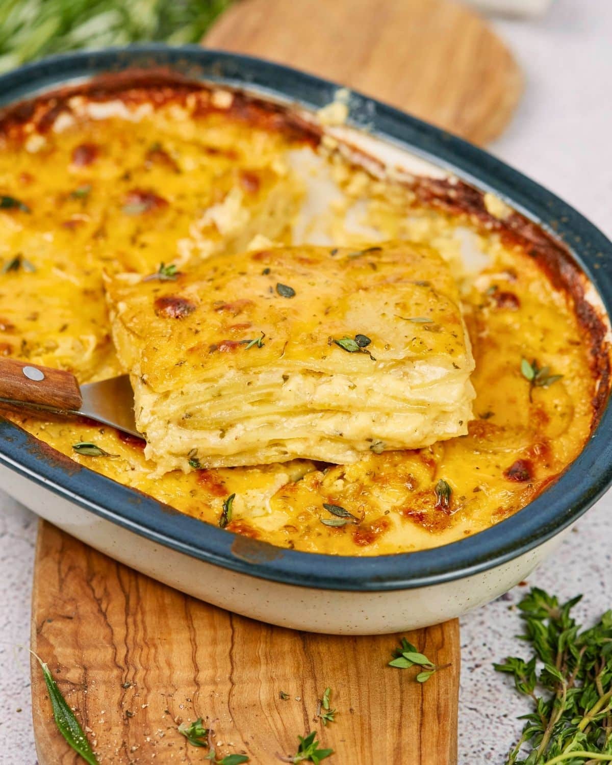 slice of scalloped potatoes held above baking dish