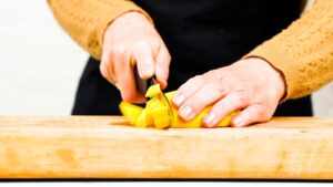 mango being sliced on wooden cutting board