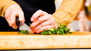 herbs being chopped on wooden cutting board