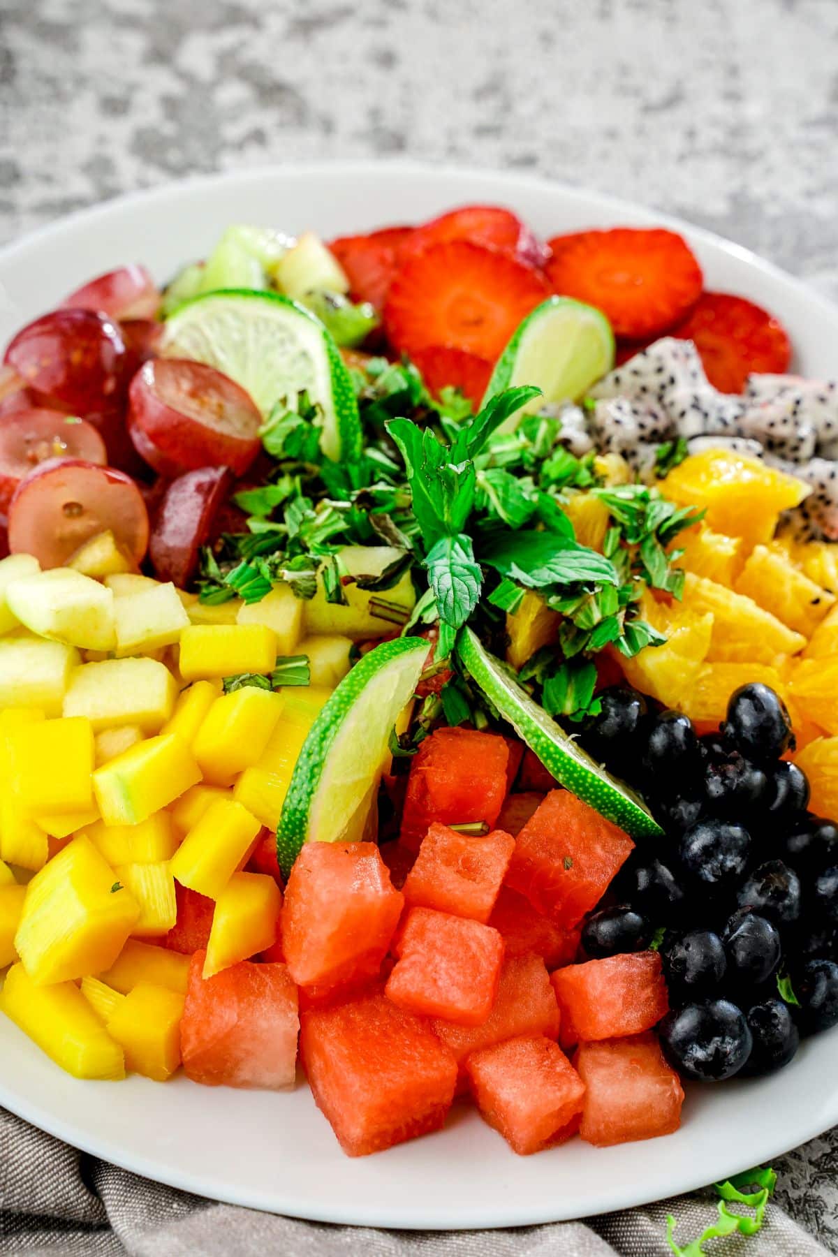 white plate of diced fruit on gray marble table