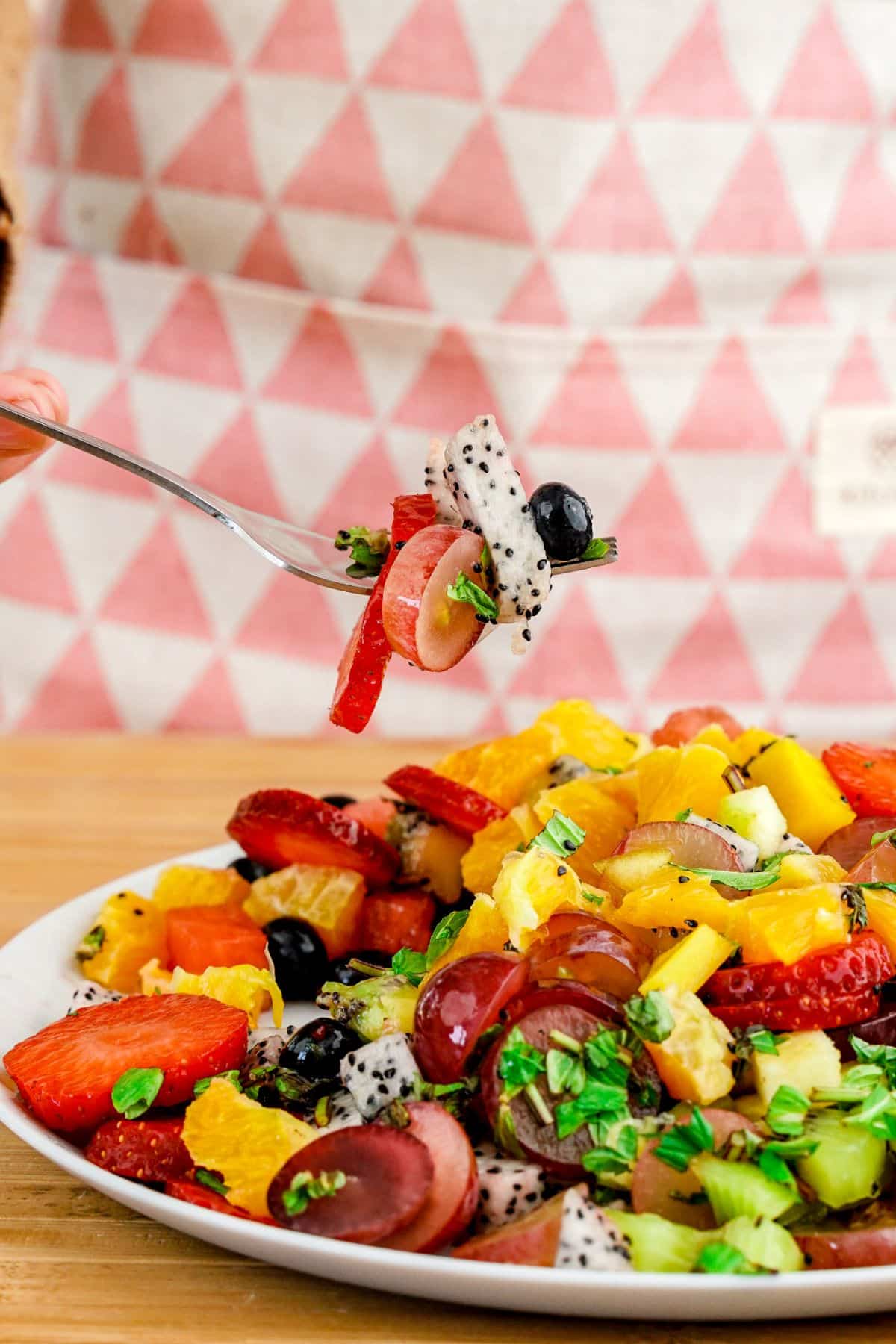 fork of fruit salad held above plate