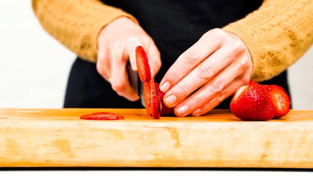 slicing strawberries on cutting board