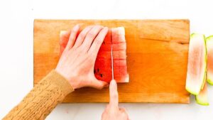 watermelon being sliced on wooden cutting board