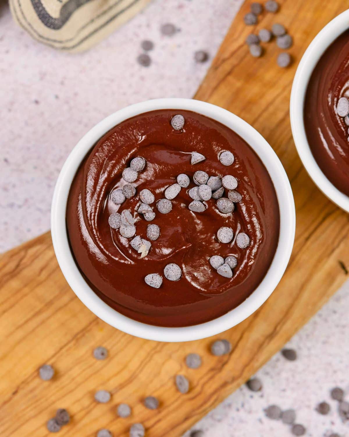 white ramekin of vegan chocolate pudding topped by mini chocolate chips