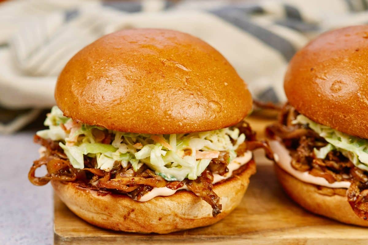 two vegan pulled pork sandwiches on wooden platter