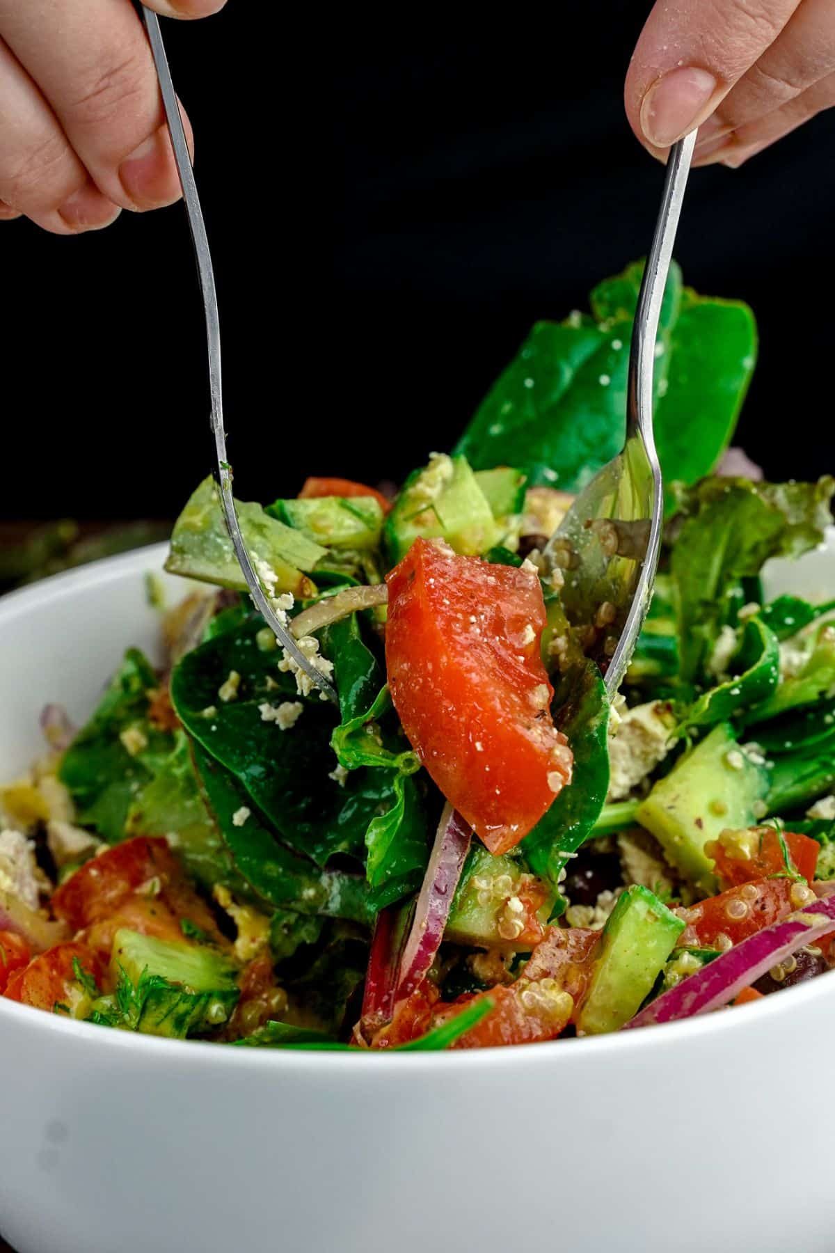 forks tossing spinach quinoa salad