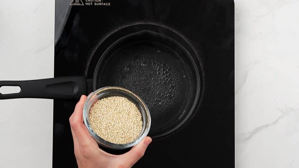quinoa being poured into boiling water
