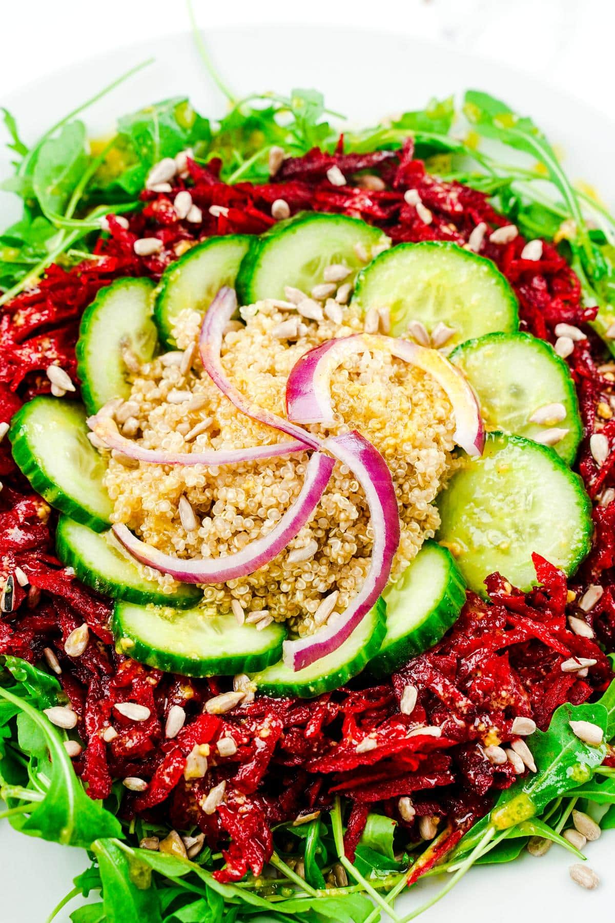 salad on white bowl with red onion and cucumber slices on top