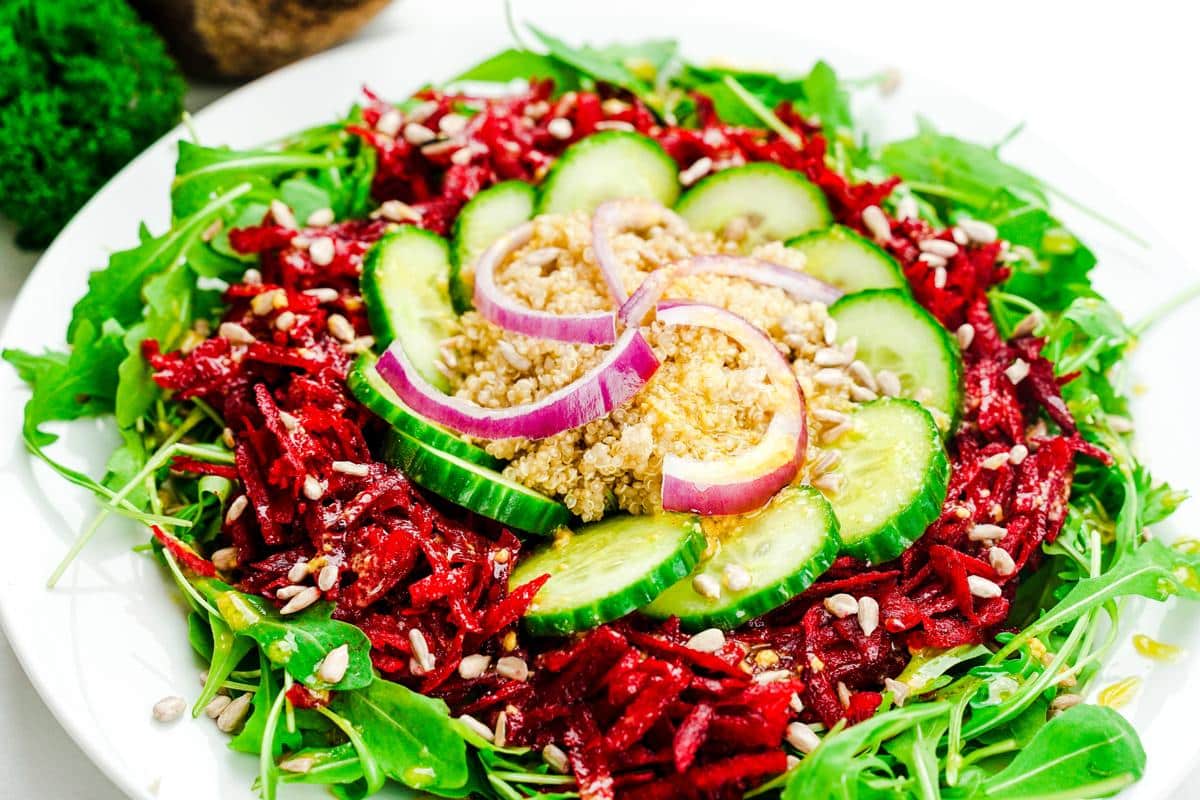 grated beets, cucumber, and quinoa on top of arugula salad