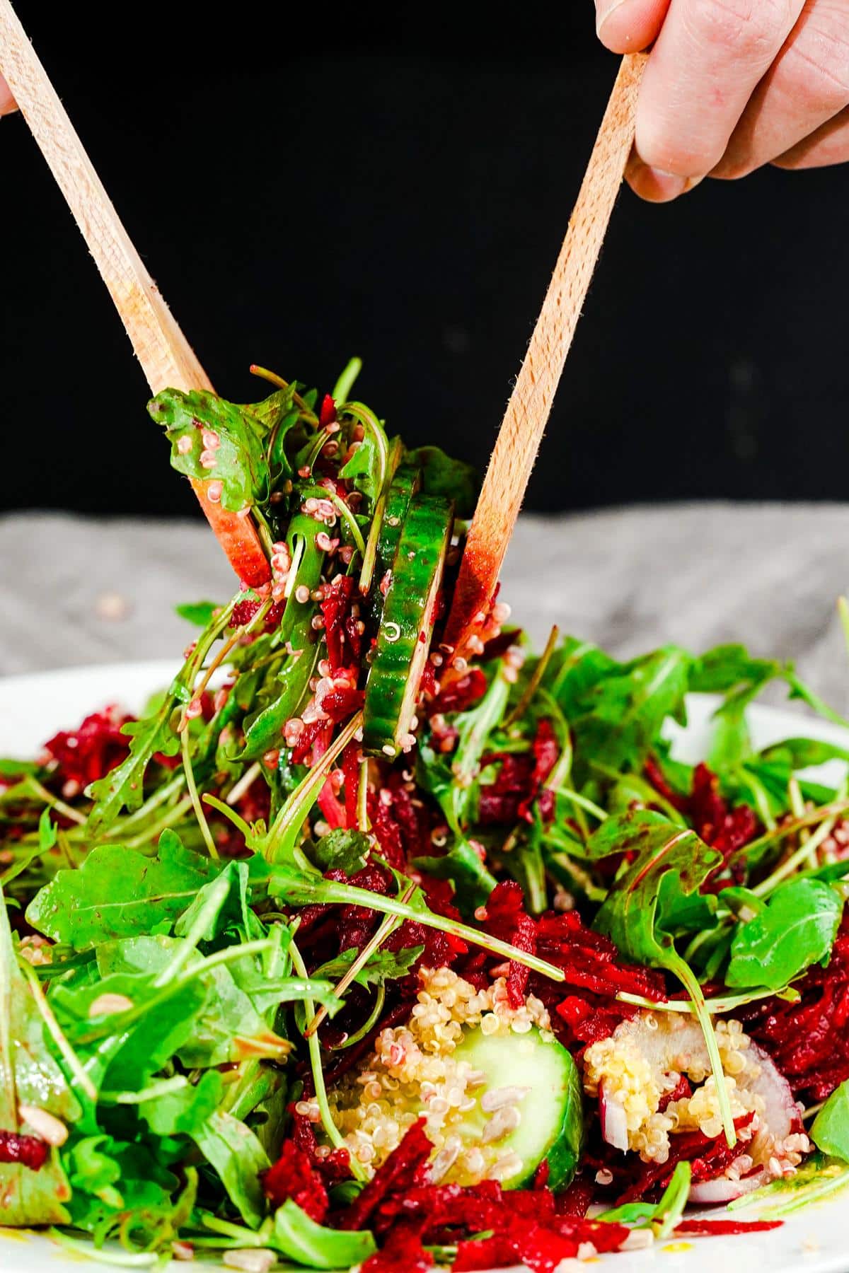 wooden spoons tossing salad above plate